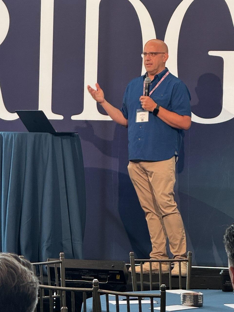 Kris Hagel speaking on stage at Bridges 2026 in New York City