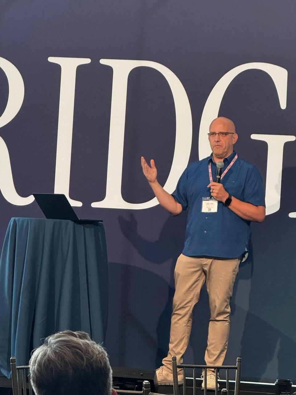 Kris Hagel speaking on stage at Bridges in New York City